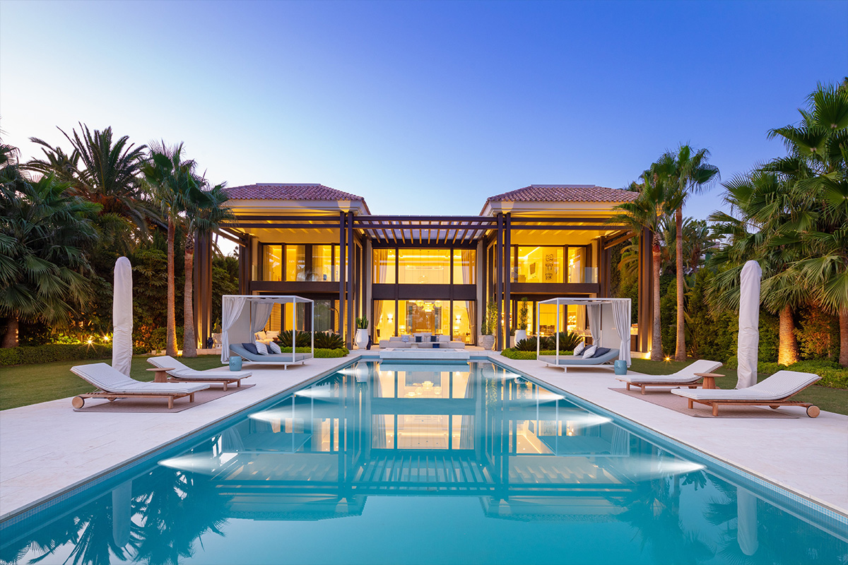 Luxury resort villa at dusk with lap pool and palm trees